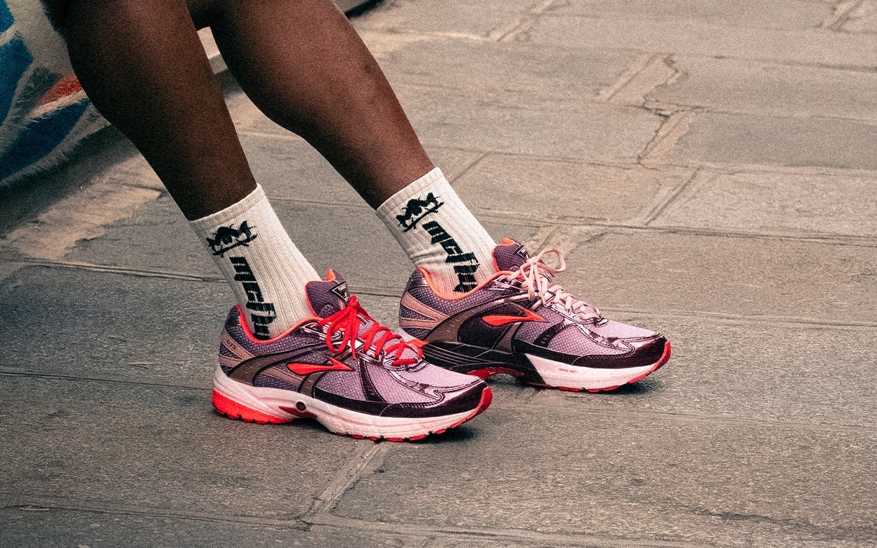 A person wearing Brooks shoes on a sidewalk