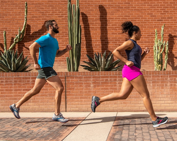 Side view of two runners on a sunny day, with cacti in the background