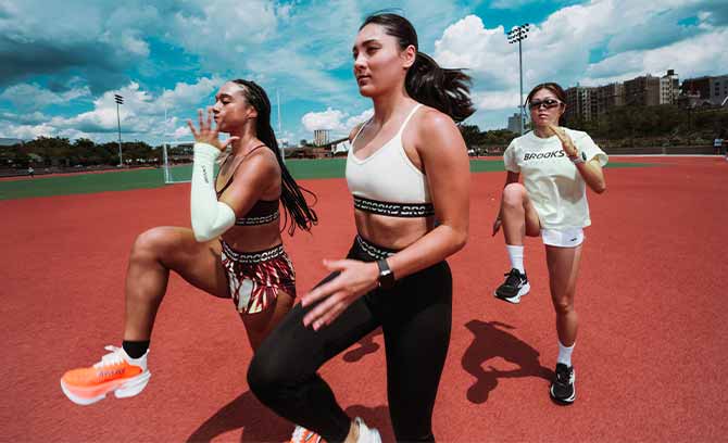 Three runners wearing Brooks gear stretch outside