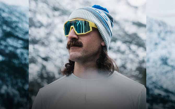 Man wearing Brooks gear stands in front of a snowy background