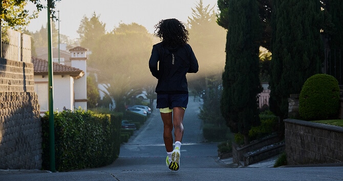 A person runs down a sunny sidewalk