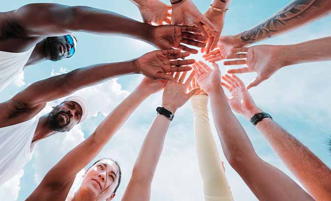 A group of people bring their hands together in a circle