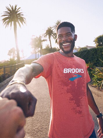 Man wearing a red Brooks t-shirt giving a fist bump