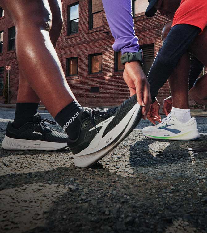 A person wearing Brooks shoes stretches outside