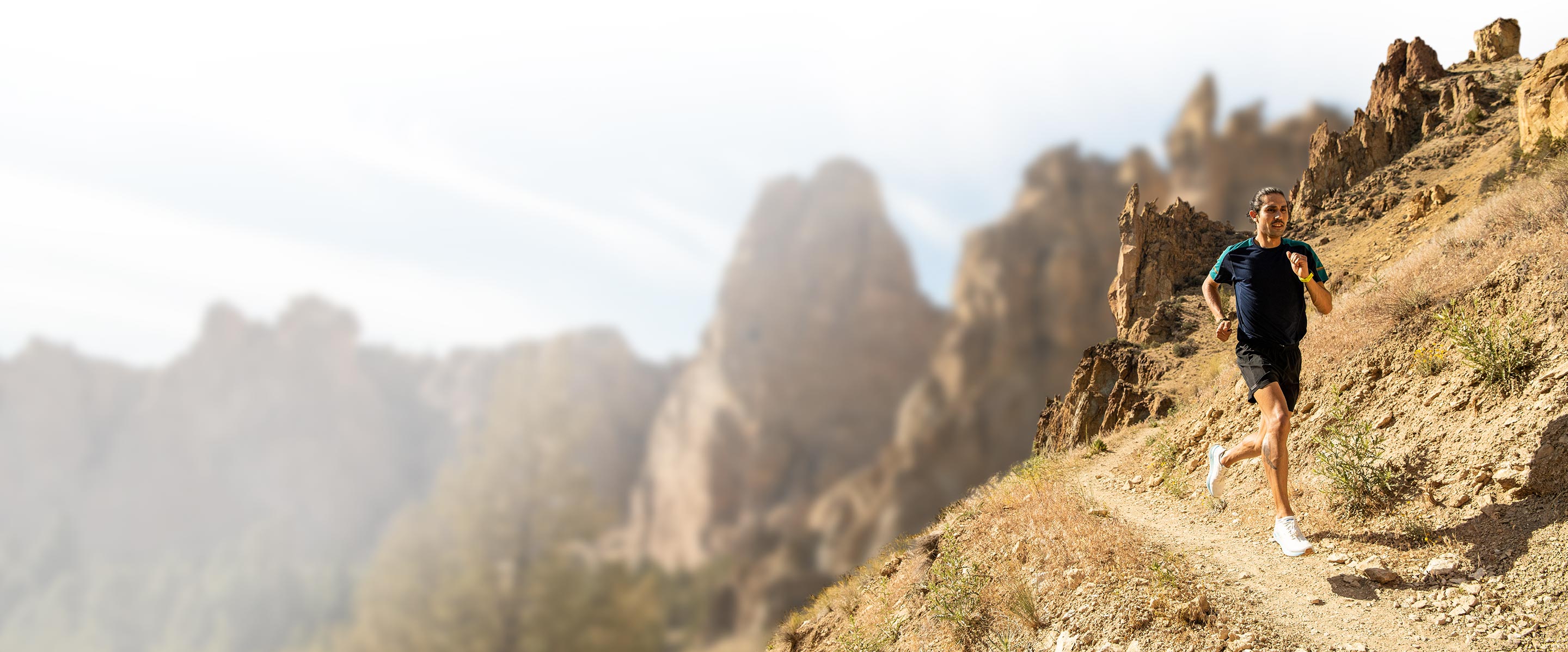 A runner runs along a desert trail wearing the Catamount trail shoe. 