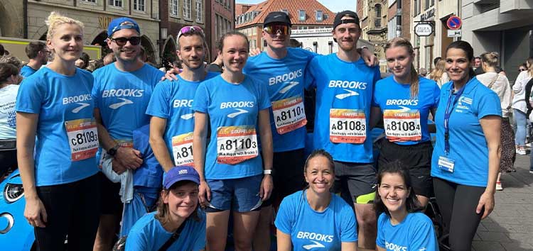 Des personnes portant une chemise Brooks et souriant à l’extérieur