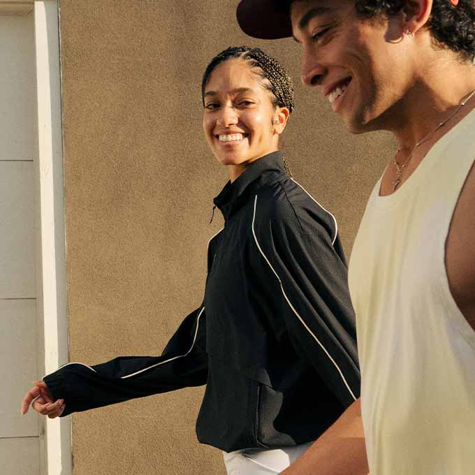 A man and a woman walk side-by-side, smiling