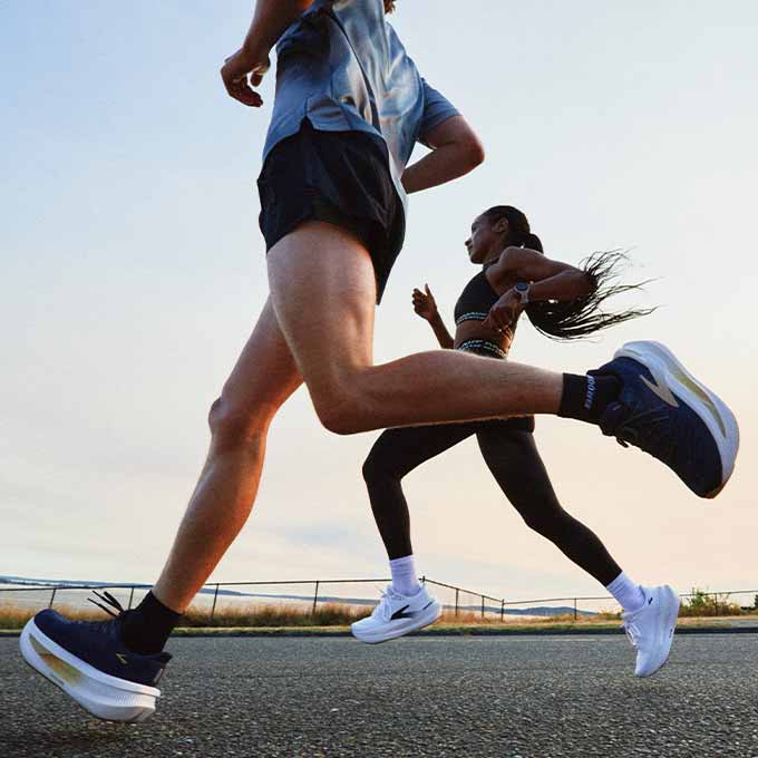 Two people run in Brooks gear against a sunset.