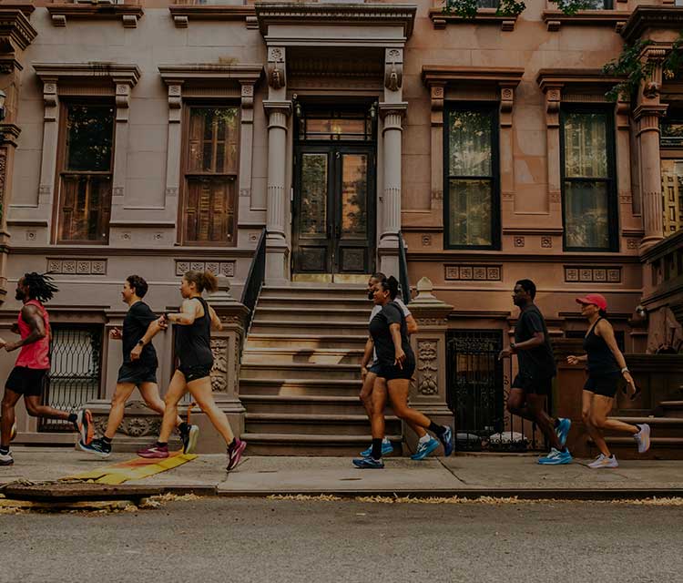 A group of people walk along the sidewalk in front of a city building