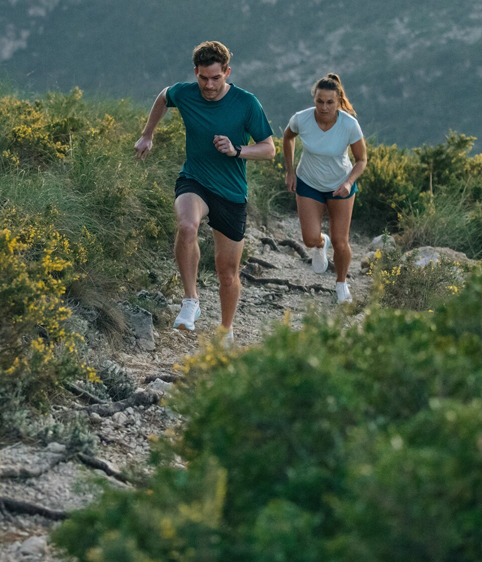 Two trail runners run at an incline on a rocky surface wearing the Catamount trail shoe. 