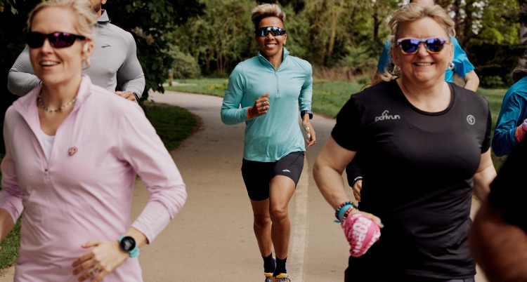 Medium shot of a group of runners wearing Brooks gear in the park