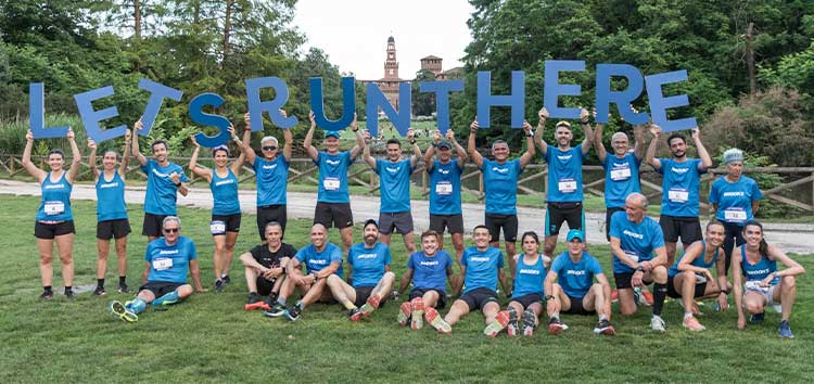 Des personnes portant des chemises bleu vif tiennent un panneau indiquant « Let’s run there »