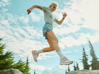 A person wearing Brooks shoes jumps in a forest