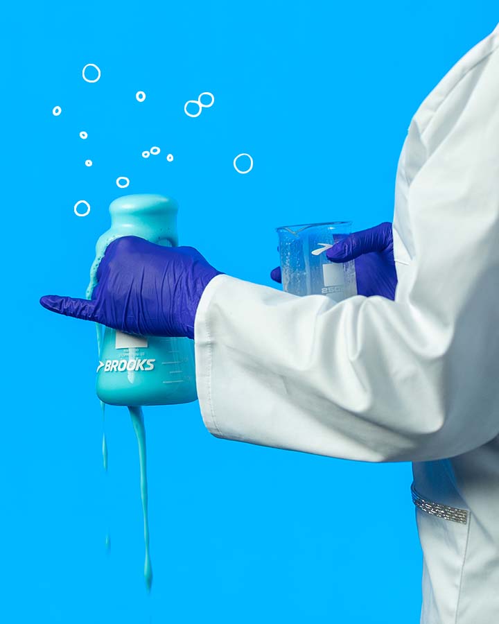 Person wearing lab coat and gloves with a nitrogen-filled beaker