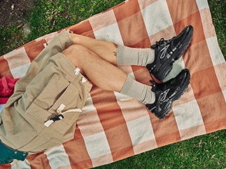 A person wearing Brooks shoes lies on a picnic blanket