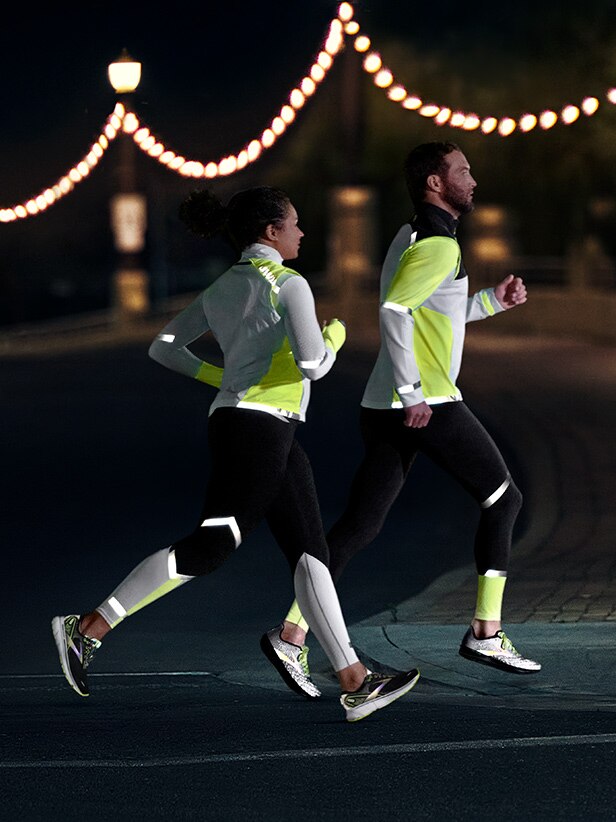 Side view of a woman and a man running in the dark
