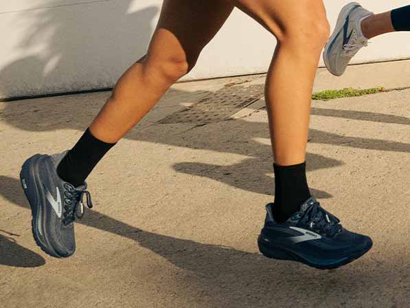 A person in Brooks shoes running on a sidewalk on a sunny day