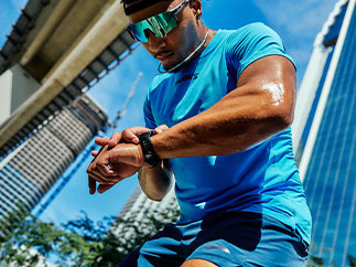 A man in Brooks apparel looks down, a blue cityscape behind him