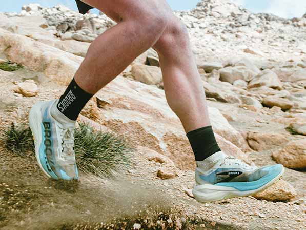 A person in Brooks shoes walks down a rocky trail