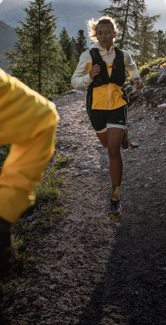 Medium shot of a woman and a man running on the Brooks trail gear