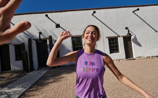 A runner smiles and high-fives someone behind the camera after a run.