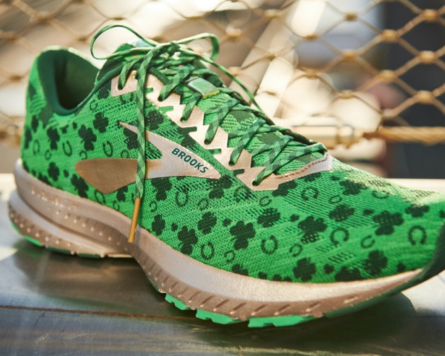 A green shoe with shamrocks and a gold sole