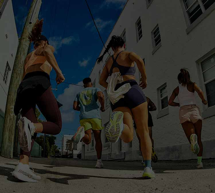 A group of people run down a sidewalk on a sunny day
