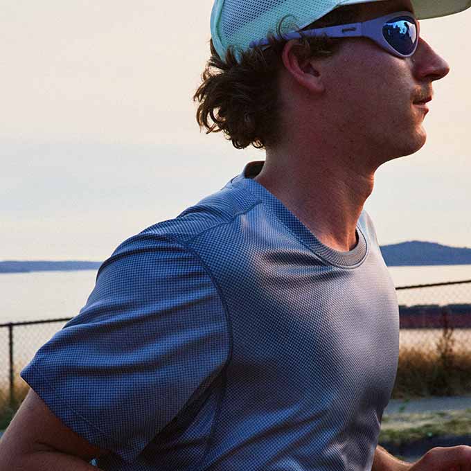 A man looks to the side, running against a sunset.