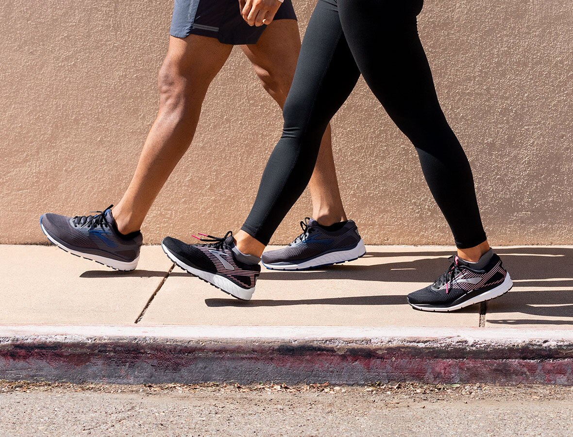 A picture of two people from the waist down walking on a sidewalk; they are both wearing the Addiction 14 in black