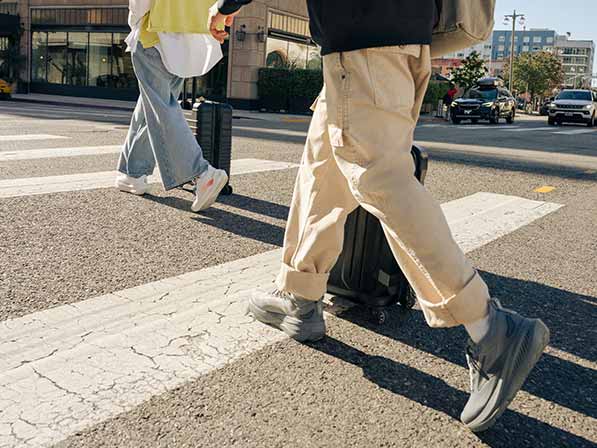 Two people wearing Brooks shoes and casual clothing walk across a crosswalk.