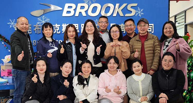 A group of people smiling in front of a Brooks sign