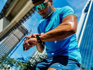 A man in Brooks apparel looks down, a blue cityscape behind him