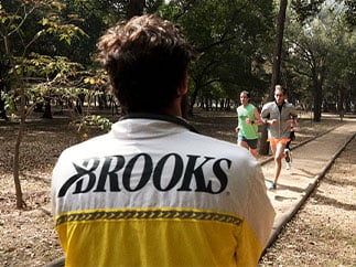 Homme portant une veste Brooks regardant des coureurs et coureuses