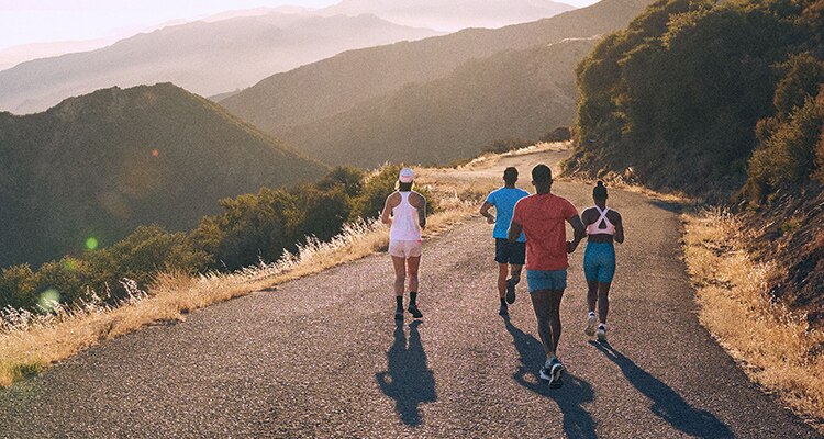 Runners with Brooks gear running on a road in between mountains.