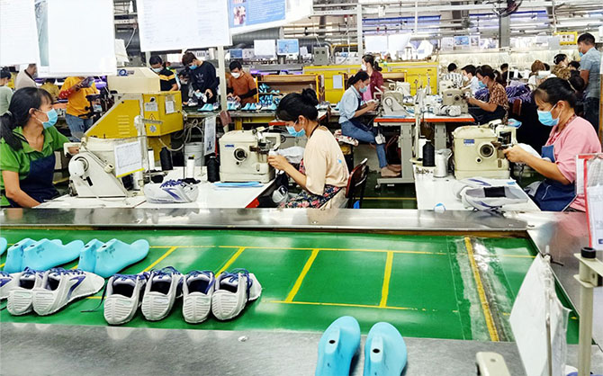 Employés et employées fabriquant des chaussures dans une usine