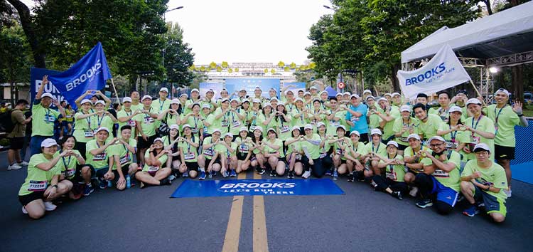 A group of people standing behind a Brooks banner