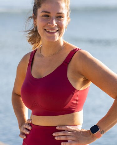 Gros plan sur une femme portant une brassière de running Dare et souriant à la caméra.