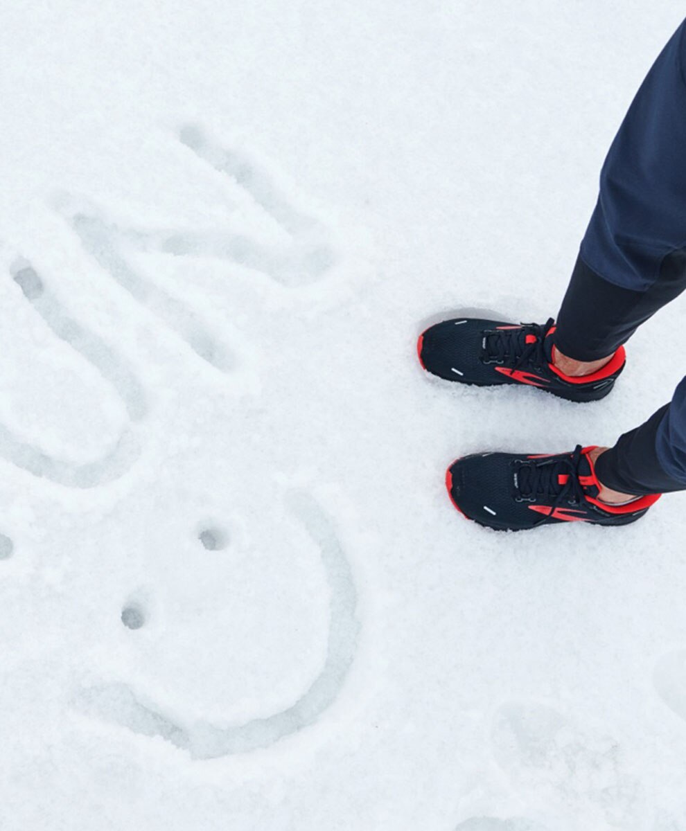 Feet in the snow with "run" written in snow