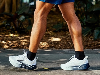 A closeup of a person walking and wearing Brooks shoes