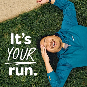 Homme souriant allongé sur l’herbe avec les mots « C’est votre course » à côté de lui