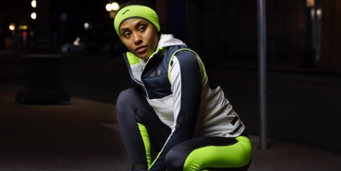 A woman tying her shoe outside in reflective gear