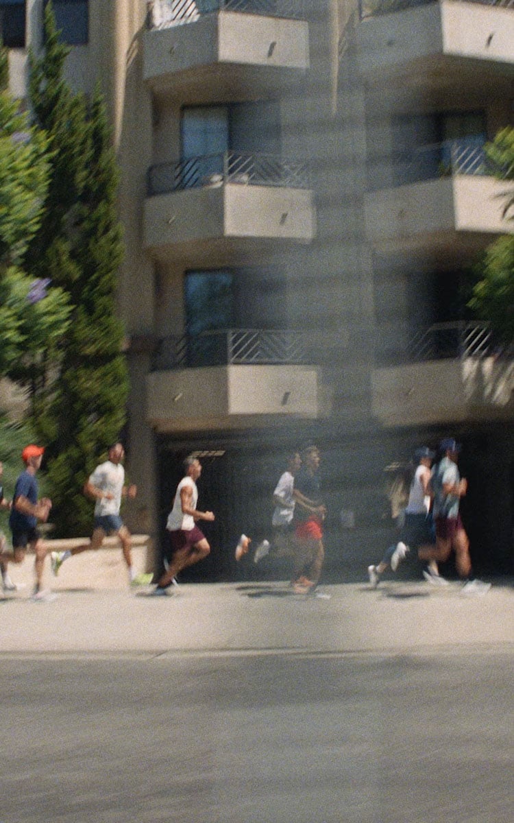 A group of people running outside a building on a sunny day