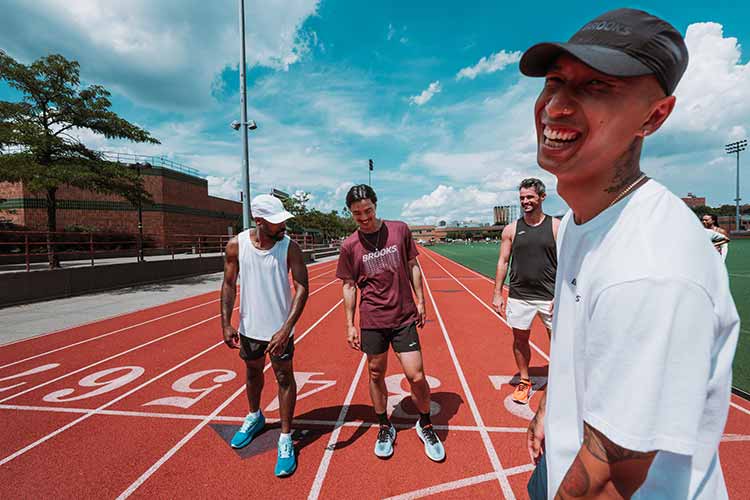 A group of smiling runners outside on a track