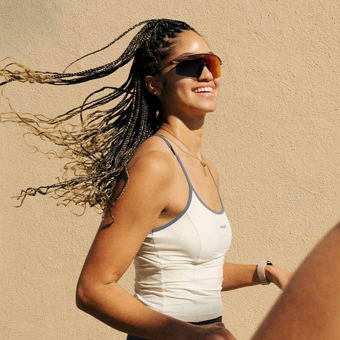 A smiling woman runs on a sunny day wearing the Movement Built-In Bra Tank