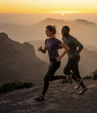 Two runners on a trail at sunrise