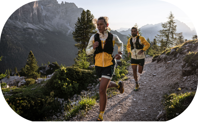 Long shot of a woman and a man running on a mountain and wearing the brand-new Brooks trail clothing