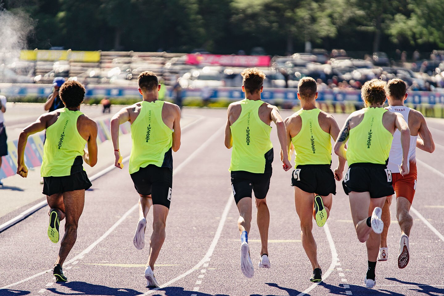 Athletes running on a track from behind in bright yellow uniforms