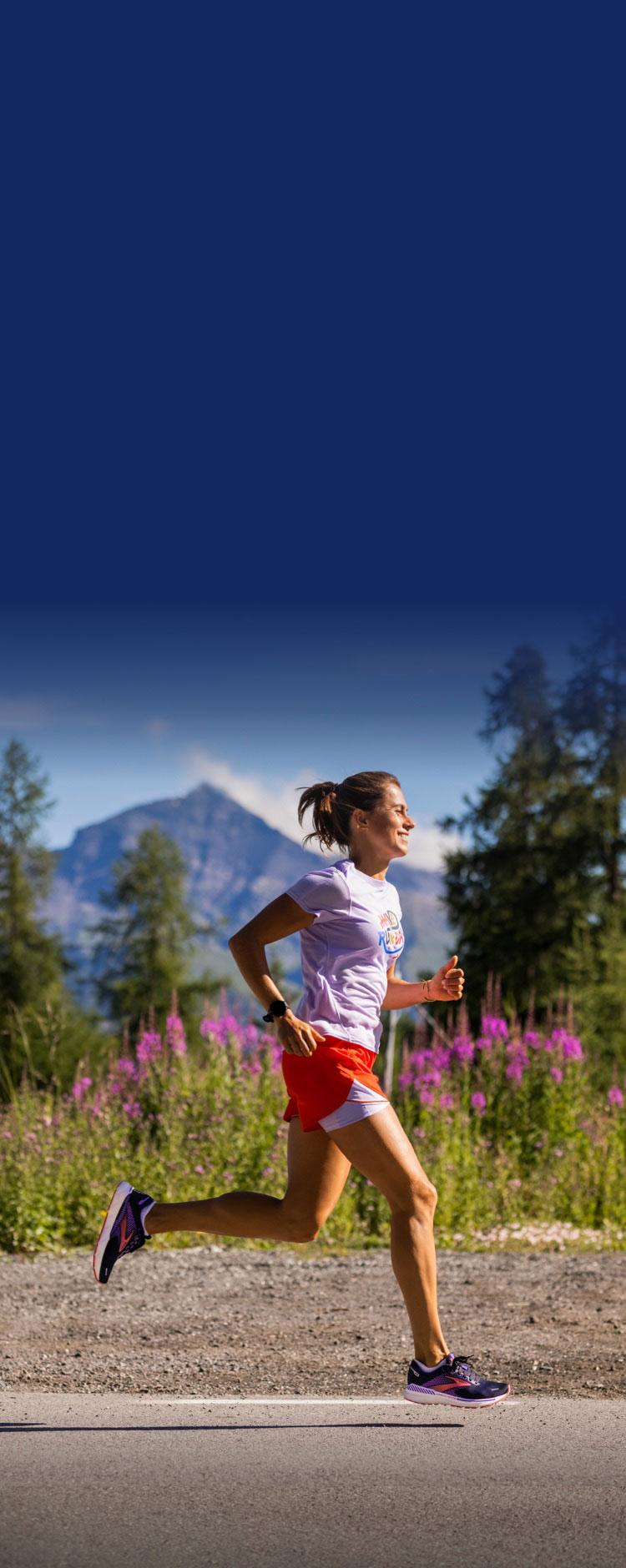 Female runner on road with flowers and mountains in the background