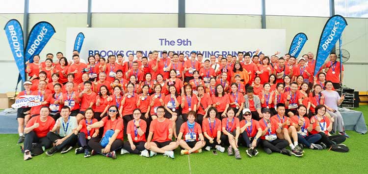 A group of people stand in front of a Brooks banner