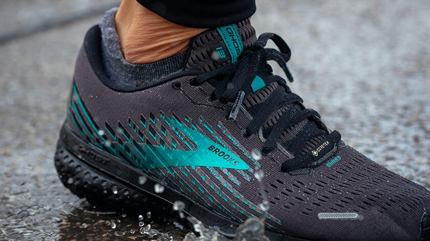  A close-up shot of the waterproof Ghost GTX running shoe splashing through a puddle.